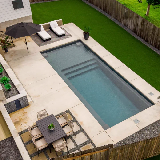 Top-down drone view of an Ovation 30 rectangular fiberglass pool in Gibraltar Grey with splash pad and bench.