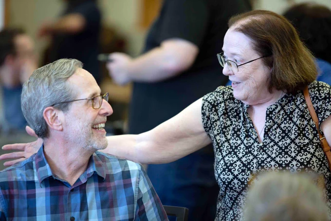 Pictured is a photo of UTA Libraries staff member Andrew Leverenz talking with a fellow staff member at his retirement party.