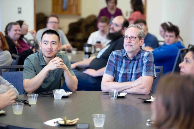 Pictured is a photo of UTA Libraries staff member Andrew Leverenz sitting at a table listening to speakers at his retirement party on May 27.