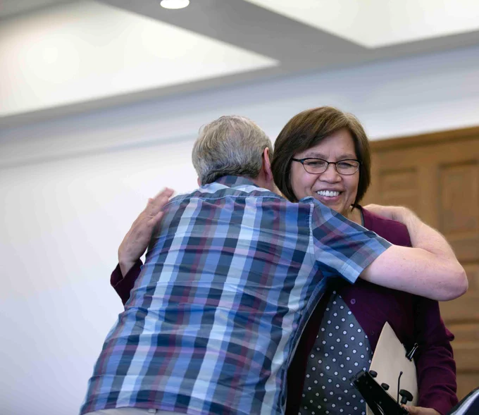 Pictured is a photo of UTA Libraries staff member Andrew Leverenz hugging another staff member at his retirement party.