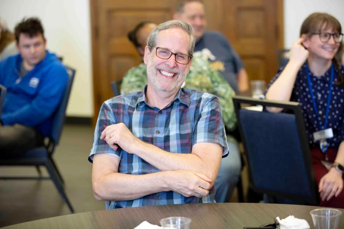 Pictured is a photo of UTA Libraries staff member Andrew Leverenz sitting at a table.