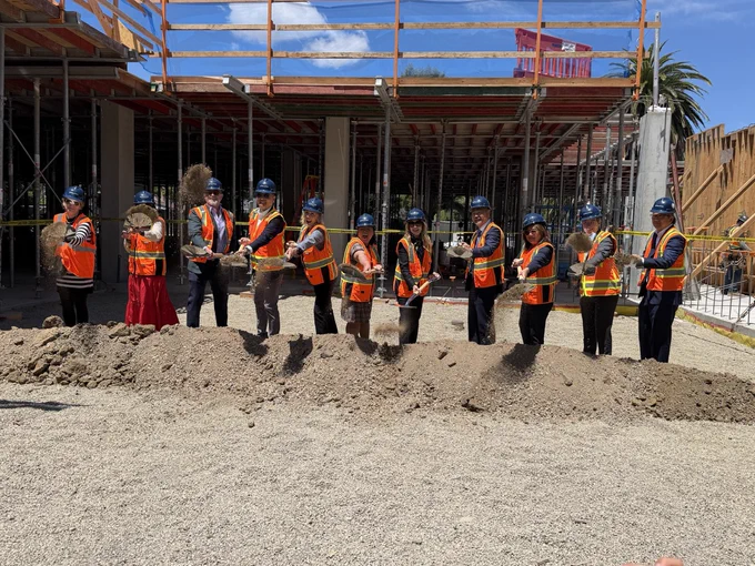 Photo of partners shoveling dirt during the groundbreaking ceremony for Corso Apartments.