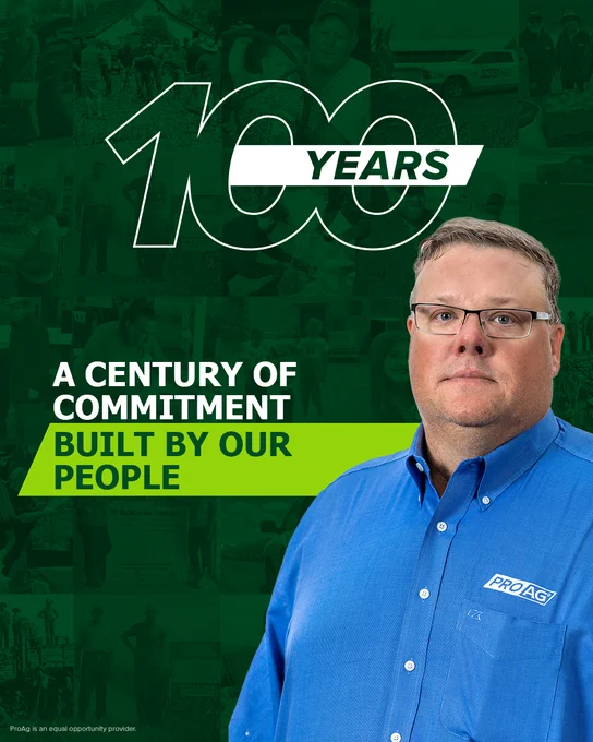 Nored Lane stands in the foreground of an anniversary poster. The poster features the text "100 Years" and "A Century of Commitment Built by Our People." Various background images depict agricultural scenes.