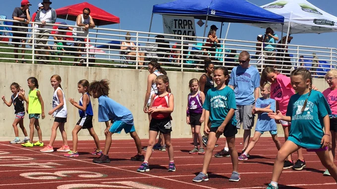 Young girls line up at the start getting ready to run a race on the track.