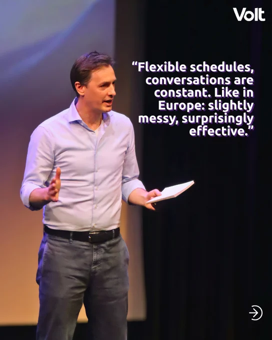 A man in a light blue shirt and dark trousers speaks passionately on a stage, gesturing with his hands and holding a small notebook. Overlaid text reads: "Flexible schedules, conversations are constant. Like in Europe: slightly messy, surprisingly effective." The Volt logo is in the top right corner.