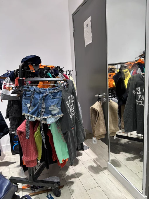 Accessible changing room door blocked by a rack covered in clothes.