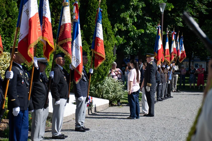 Le préfet des Hautes-Pyrénées se tenant devant la gerbe de fleurs qu’il vient de déposer, entouré de porte-drapeaux alignés portant les couleurs tricolores. 
