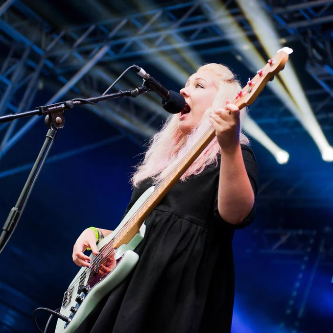 Woman playing a guitar and singing, on stage 