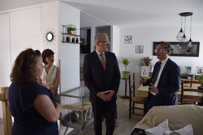 Échange entre le préfet des Hautes-Pyrénées, le maire de Lourdes et deux femmes à l'intérieur d'un des logements moderne et meublé.