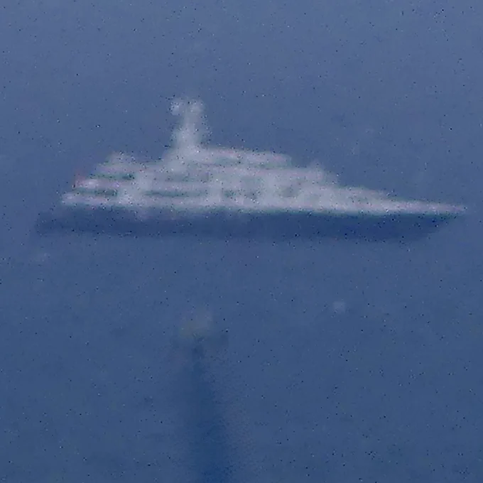 Indistinct image of superyacht at anchor in the far distance.