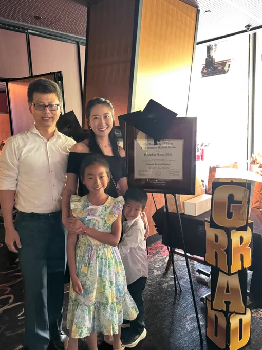 Dr. Shanshan Tang standing with her degree and family members.