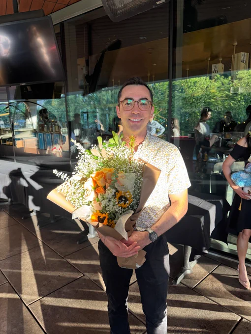 Dr. Jacob Buatti holding a bouquet of flowers at graduation.