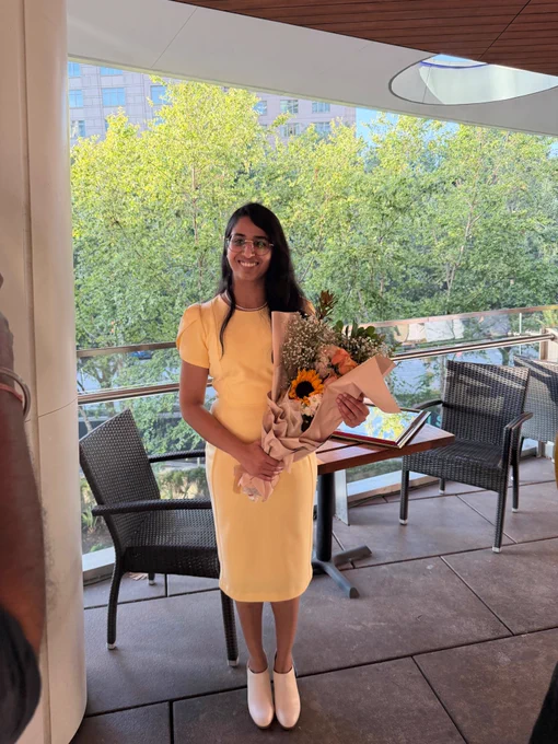 Dr. Sruthi Sivbhaskar holding a bouquet of flowers at graduation.