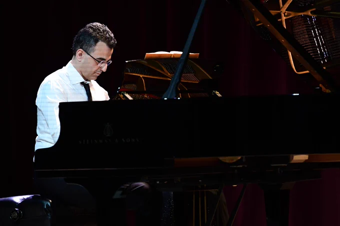 A person seated at a Steinway & Sons grand piano, focusing intently while playing.