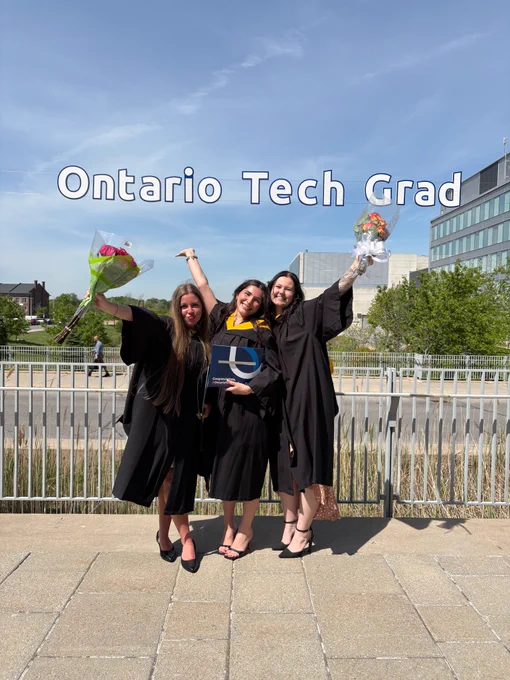 Three graduating students posing for a photo under a banner that says “Ontario Tech Grad.”
