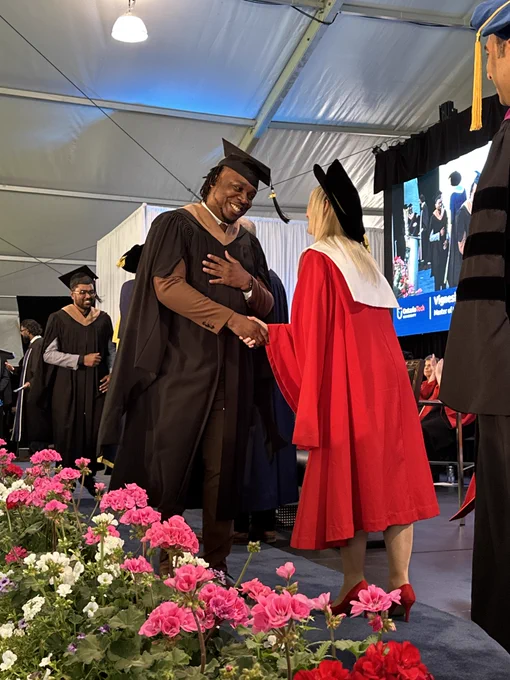 A graduate on stage shaking hands with a faculty member.
