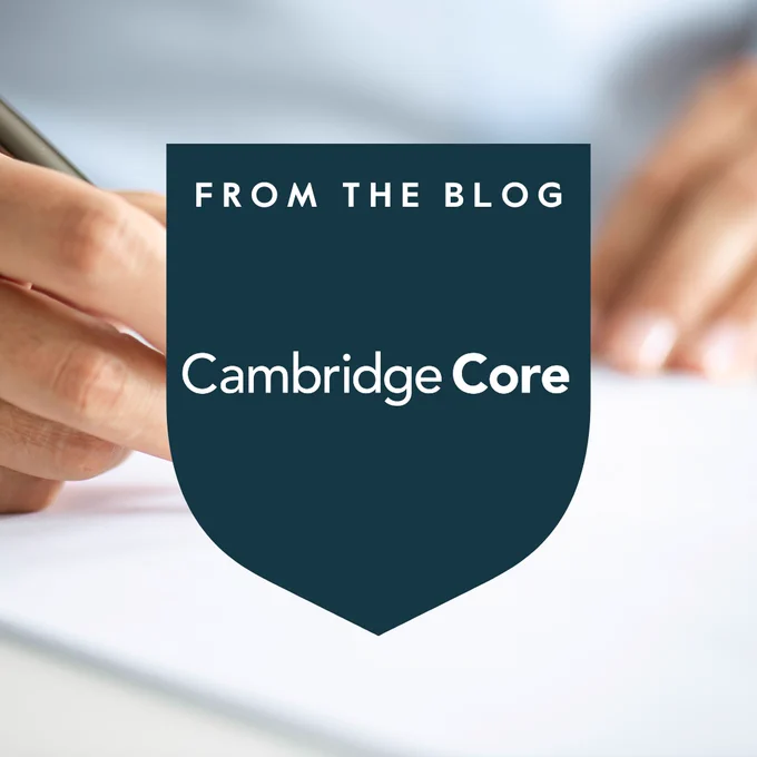 The image features a close-up of a hand writing with a pen on a piece of paper. Overlaid in the center is a dark shield shape with the words "From the Blog" at the top and "Cambridge Core" in the middle.