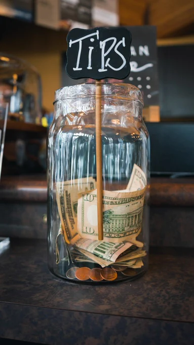 Photo of a tip jar with money in it. 