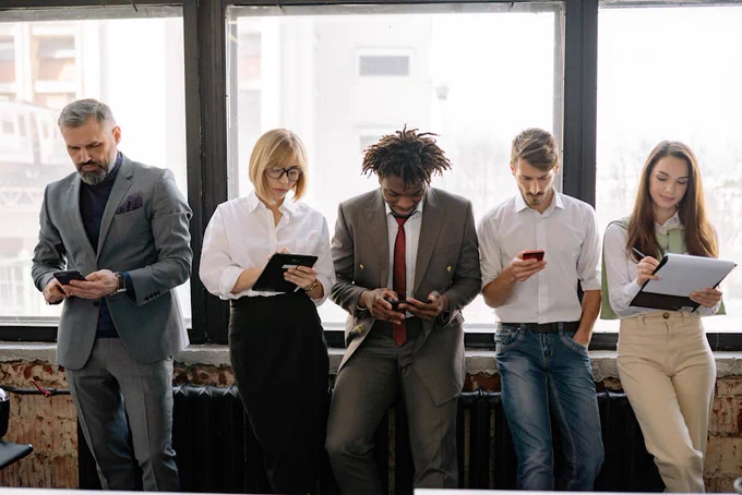 A diverse group of colleagues using mobile devices in an office setting.