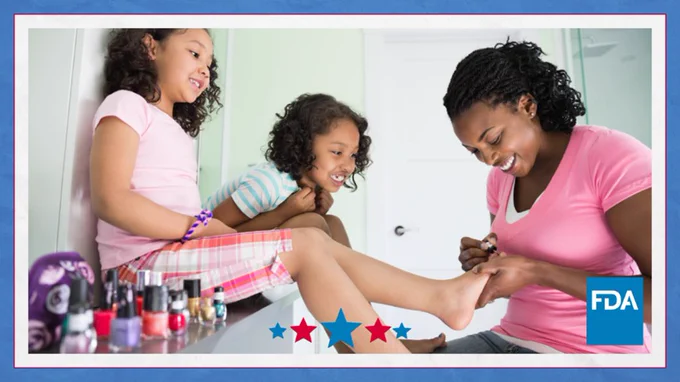 Image of a mother painting the toenails of her daughters with nail polish. 