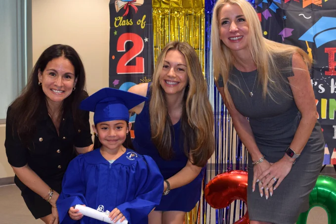 (Group Photo) Karla Richey, Caterina Camaiani, and Natalie Tappert smile for the camera with a Miami Lighthouse Academy Pre-K graduate