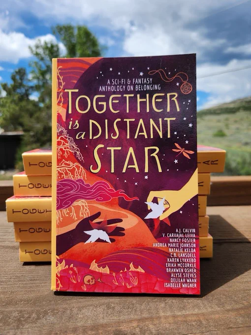 The Together is a Distant Star anthology sitting on a wooden table with a backdrop of the Colorado foothills, a tree, and a partly clouded sky.