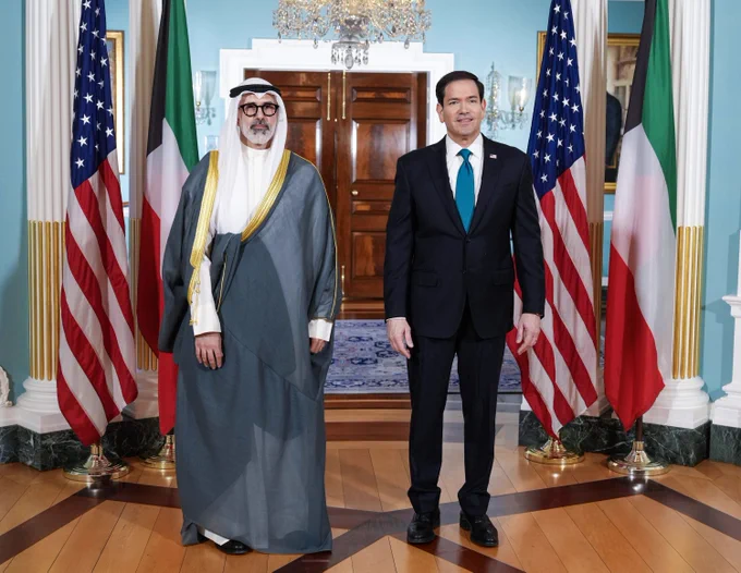 Secretary Rubio stands next to Kuwaiti Foreign Minister Sheikh Jarrah Jaber Al-Ahmad Al-Sabah in Washington, DC on June 3, 2026. They stand between and slightly in front of two sets of U.S. and Kuwaiti flags. A rug, chandelier, wall sconces, and wood double doors are visible in the the room behind the officials. (State Department/Freddie Everett)