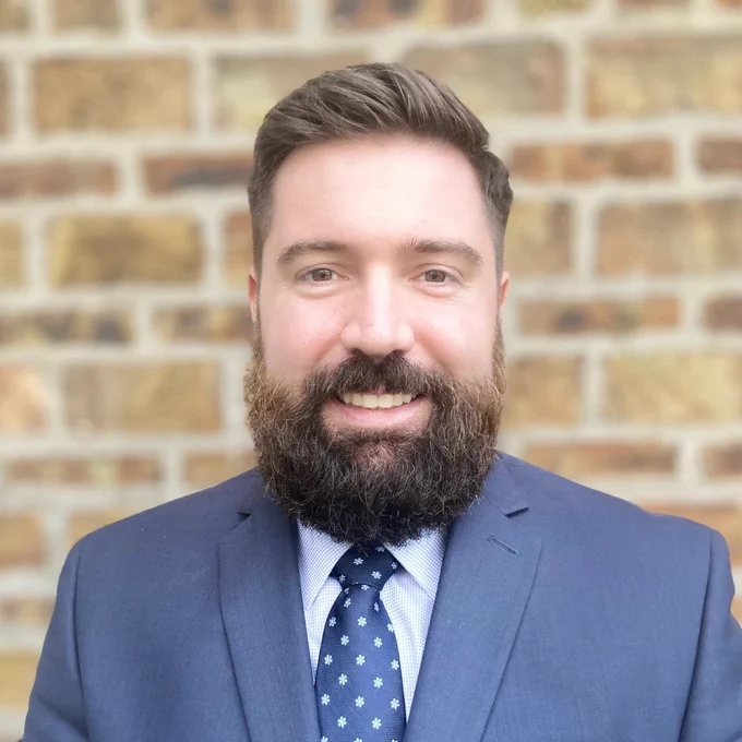 Phillip Sherlock in a suit smiling at the camera