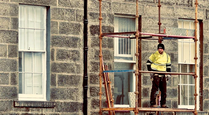Edinburgh scaffolding contractor halfway up a building. He resembles a Wester gunfighter preparing to draw.