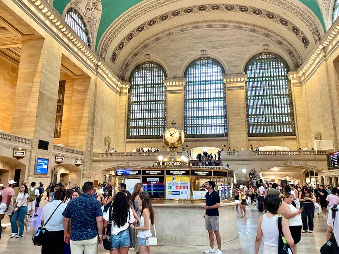 People gathered by the clock at Grand Central Terminal.