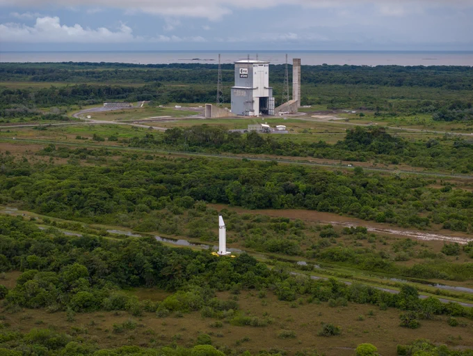 A P160C solid rocket booster being transported upright through Europe's Spaceport in Kourou, French Guiana, with the Ariane 6 launch complex visible in the background.
