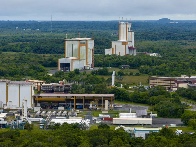 Aerial view of Europe's Spaceport in Kourou, French Guiana, showing Ariane 6 integration facilities and a P160C solid rocket booster standing upright in the middle ground.
