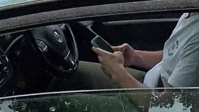The same driver a few seconds earlier using bed mobile phone when driving. Both are stills from a longer video.