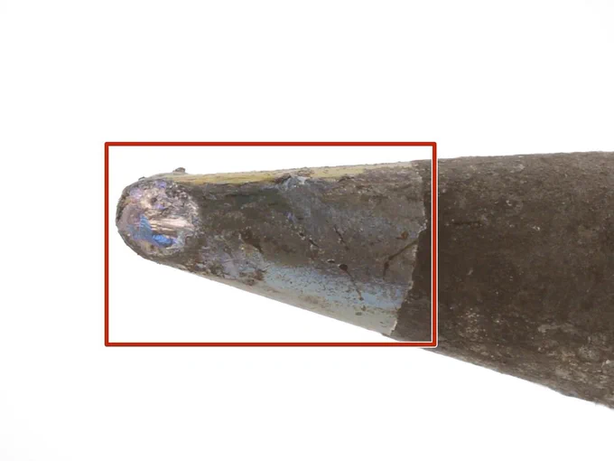Close-up of a worn soldering iron tip showing oxidation, discoloration, and pitting. A red box highlights the damaged section near the tip, illustrating signs of tip wear and the need for maintenance or replacement.