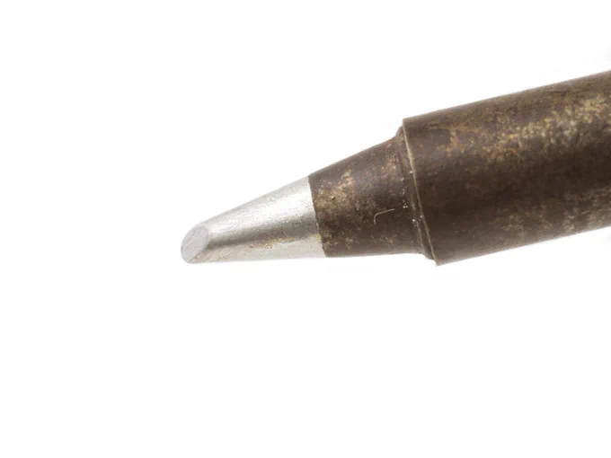 Close-up of a clean, tinned soldering iron tip. The tip has a smooth, shiny silver coating, indicating proper maintenance and an even layer of solder ready for use. White background.