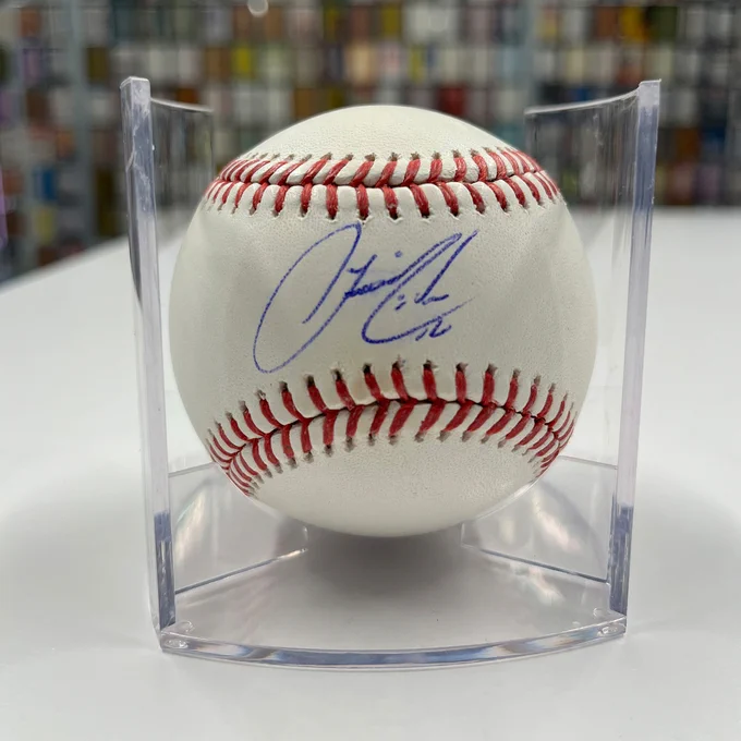 A baseball signed by Francisco Lindor. It’s sitting on a stand that is on a white table.