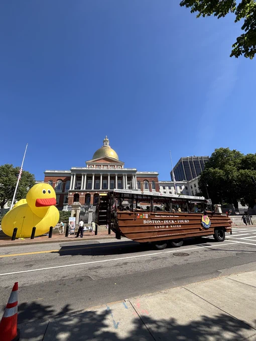 inflatable duck at the state house is passed by a duck tour boat