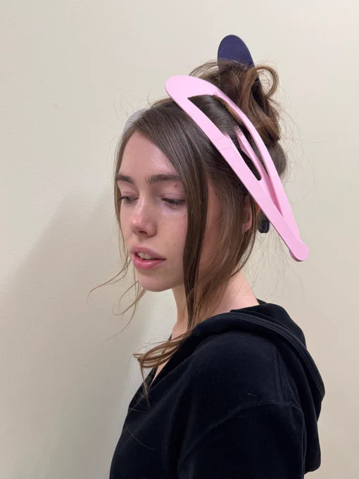 A person looking down with a large pink hair clip in their hair.