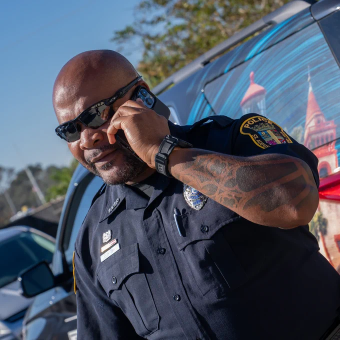 A police offer talking into an phone in front of a van.