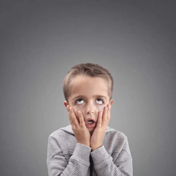 A young boy who is rolling his eyes and looking VERY bored.