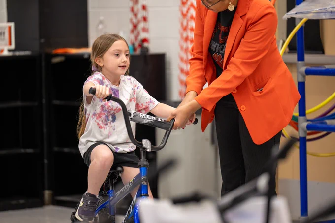 A student sits on a bike. 
