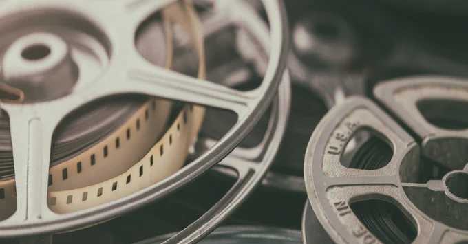 Close-up of several vintage film reels stacked on top of each other, featuring metal frames and visible lengths of film.