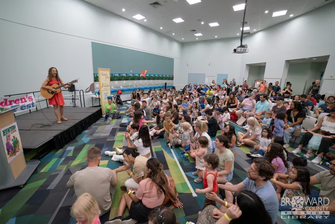 A large crowd sitting an auditorium listening to an acoustic guitar performance