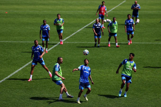 Soccer players engaged in a game with a player in blue about to head the ball