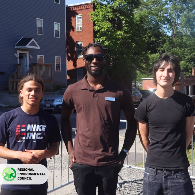 Two YouthGROW teens & a YouthGROW Alumni/Board Member, standing outdoors on a sunny day at the REC groundbreaking event. 