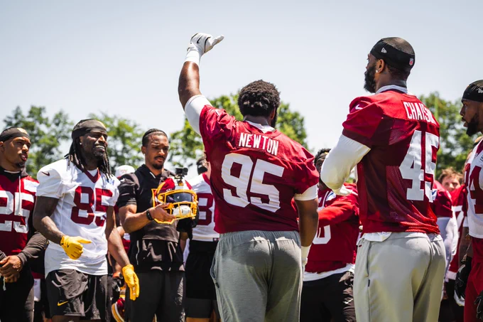 Photo of a post-practice huddle. Jayden Daniels is filming it with his GoPro helmet.