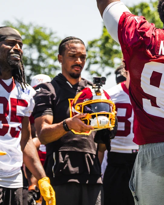 Photo of a post-practice huddle. Jayden Daniels is filming it with his GoPro helmet.