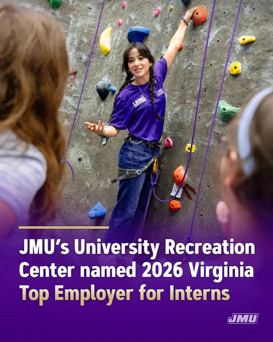 Person wearing a harness demonstrates rock climbing on an indoor wall with colorful holds while speaking to a small group in a recreation center. Overlaid text reads: “JMU’s University Recreation Center named 2026 Virginia Top Employer for Interns.” The JMU logo appears in the bottom right corner.