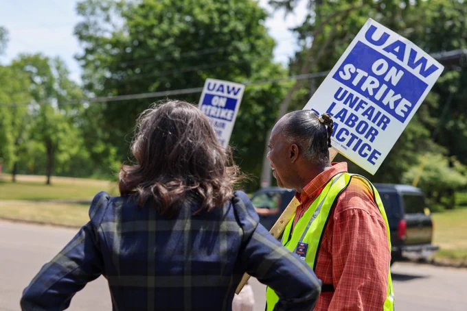 Gov. Whitmer observes a strike alongside a worker on strike.