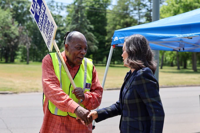 Gov. Whitmer shakes the hand of a worker on strike.